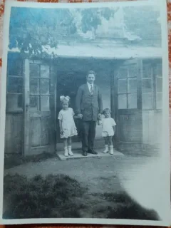 Fotografie, barbat  cu doi copii, in fata casei, perioada interbelica