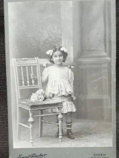 Fotografie pe carton, fetita cu fundite si buchet de flori, inceput de secol XX