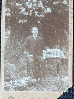 Fotografie tip CDV, Barbat la masa (Nae Andreescu comerciant), in gradina, inceput de secol XX