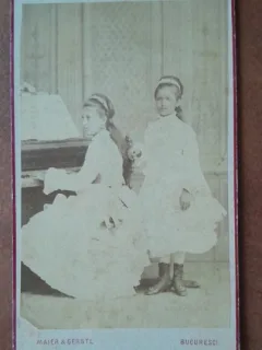 Fotografie tip CDV, doua fete, una cantand la pian, inceput de secol XX