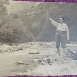 Fotografie, barbat in exursie la munte, pe malul unui parau, perioada interbelica