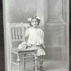 Fotografie pe carton, fetita cu fundite si buchet de flori, inceput de secol XX